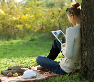 Woman with iPad under tree